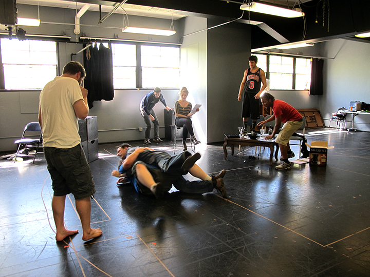 Tom Dewey works with the cast of The Financial Lives of the Poets on a fight scene, which devolves into wrestling.